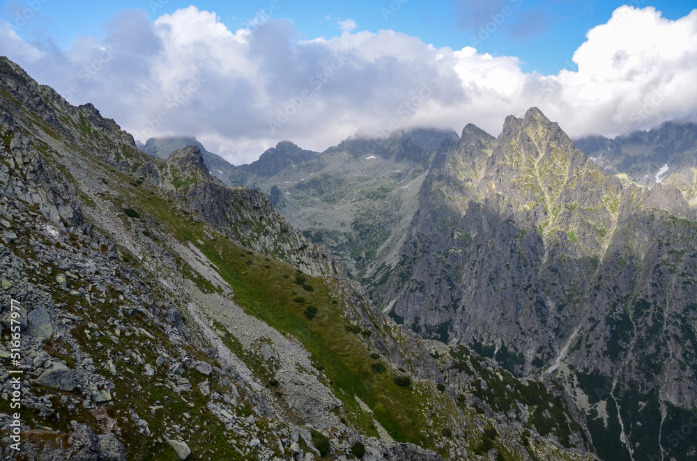 View to sharp rocky peaks covered low clouds of High Tatras mountains in Slovakia in summer. Trail to mount Slavkovsky stit 