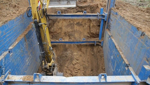 The excavator operator selects the soil from the trench, the walls of which are reinforced with trench supports. The support protects the walls from collapsing and save the workers.