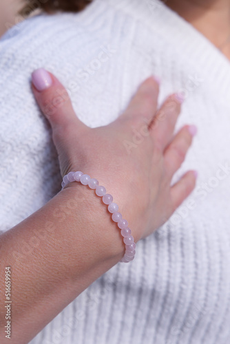 Vertical image of a bracelet made of natural rose quartz on a female hand, close-up