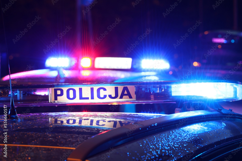 Nocna interwencja alarmowa policji - Sygnalizator błyskowy niebieski na dachu radiowozu policji polskiej w nocy. - obrazy, fototapety, plakaty 