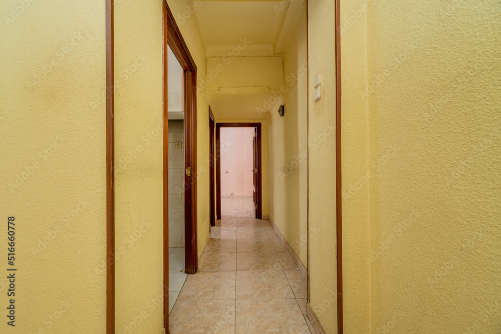 Yellow painted corridor with entrance to several rooms and ceramic tile floors