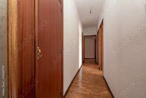 Plain white painted corridor with entrance to various rooms, fitted wardrobes and oak parquet floor