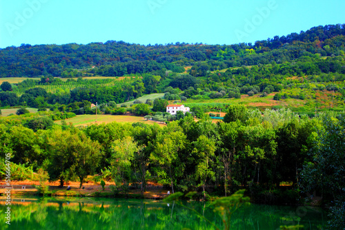 Park "I Due Laghi" in Piane di Moresco with some abundant green vegetation slowly rolling over the charismatic Marche hills with a piercing white house in the middle and translucent emerald waters