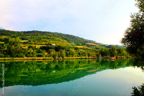 Park  I Due Laghi  in Piane di Moresco between the ridges of the typical serene and peaceful Marche hilly landscape with calm emerald waters of the lake  a tree silhouette and lush vegetation