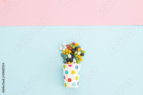 many different candies   sweets in paper cup on blue background