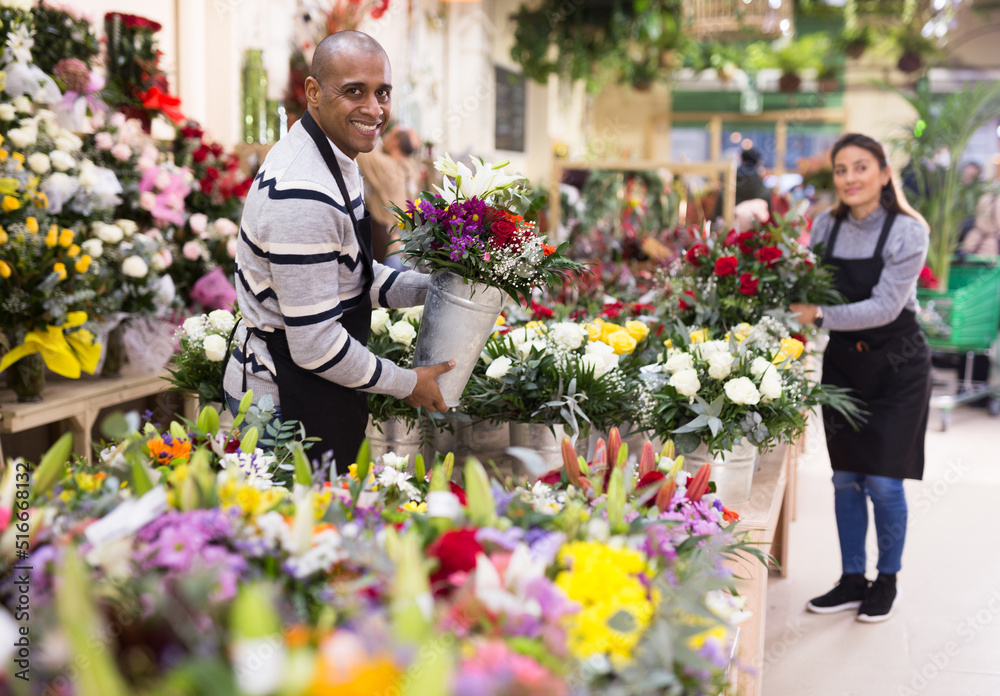 Fototapeta premium Male flower seller prepares a luxury bouquet at a flower shop