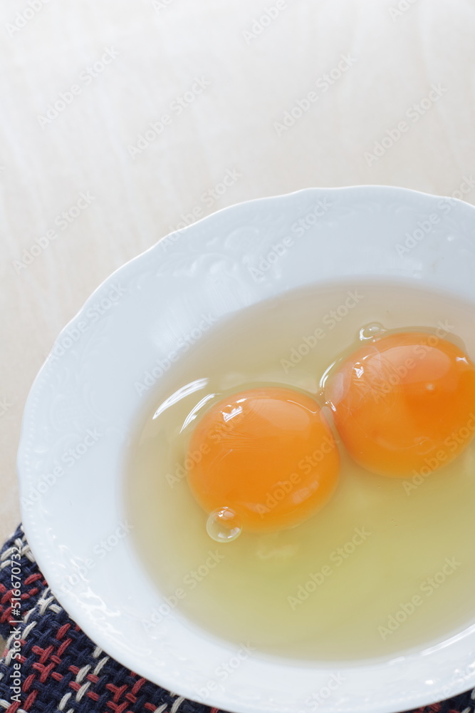 Double raw egg in white bowl with copy space Double raw egg in white bowl with copy space