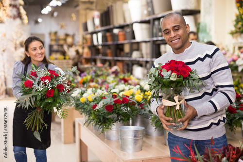 Experienced woman florist helping male client to choose flowers in flower shop © JackF