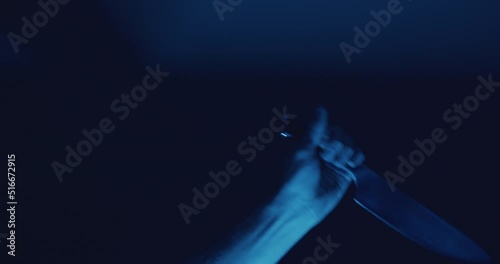 Close up of hand raising sharp knife and stabbing off camera