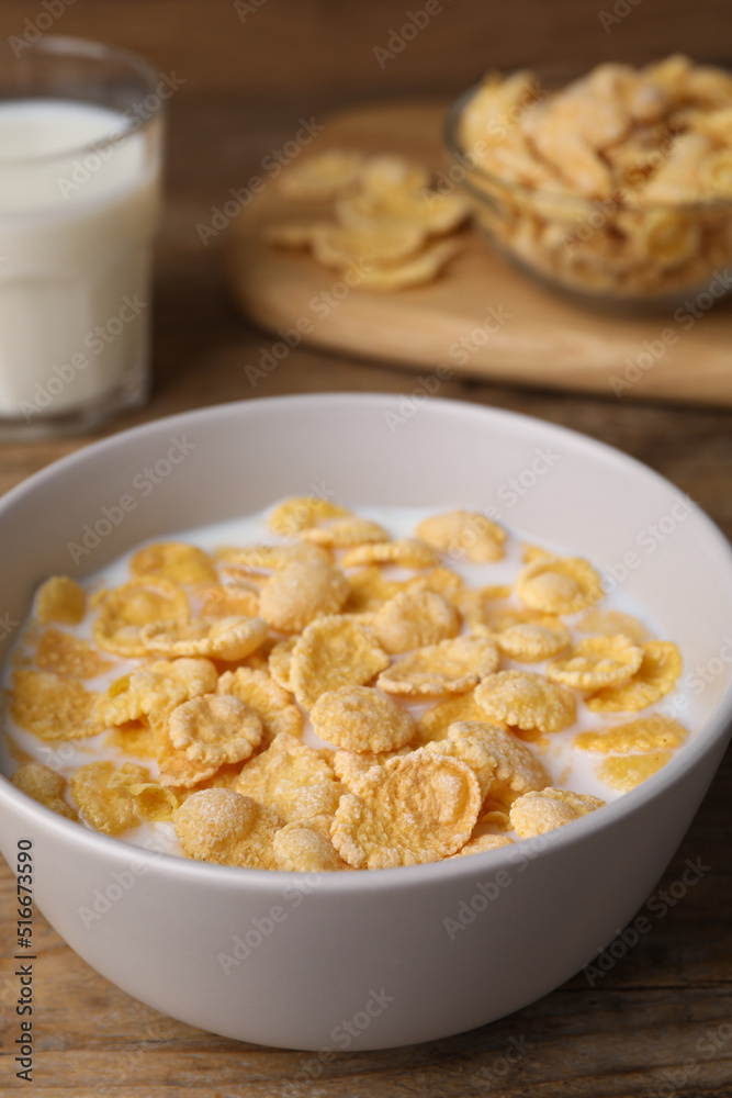 Tasty cornflakes with milk in bowl on wooden table, closeup