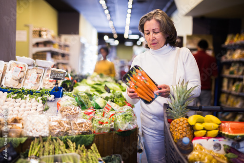 Casual aged woman doing shopping in grocery department of supermarket