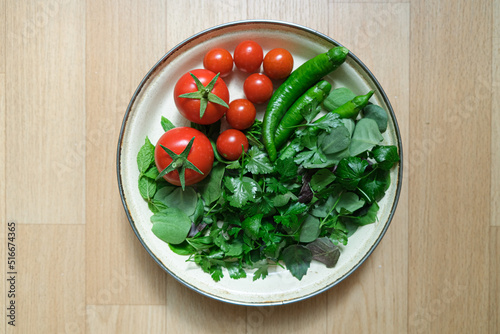 Organic some vegetables in a plate. Top view and copy space area with green vegetables and tomatoes. Tomatoes, green pepper, mint, purslane, parsley and basil in a plate.