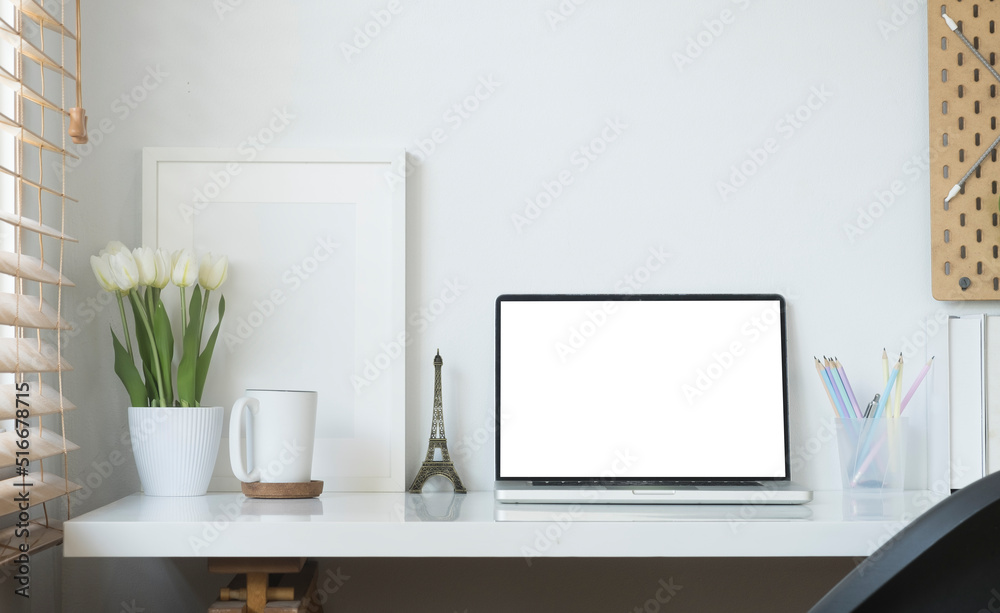 Contemporary workplace with laptop computer, picture frame, stationery and flower pot. Blank screen for your advertise text.