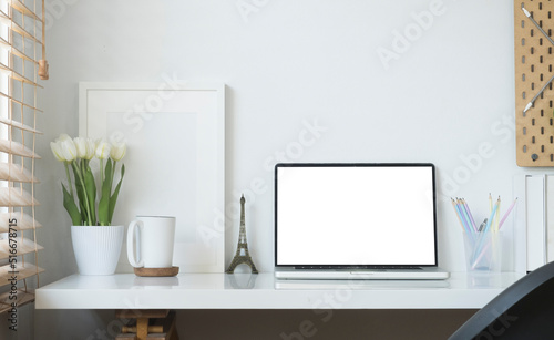 Contemporary workplace with laptop computer  picture frame  stationery and flower pot. Blank screen for your advertise text.