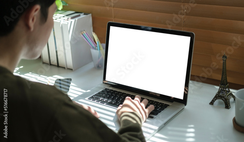 Over shoulder view of male freelancer working online, typing business email on laptop computer.