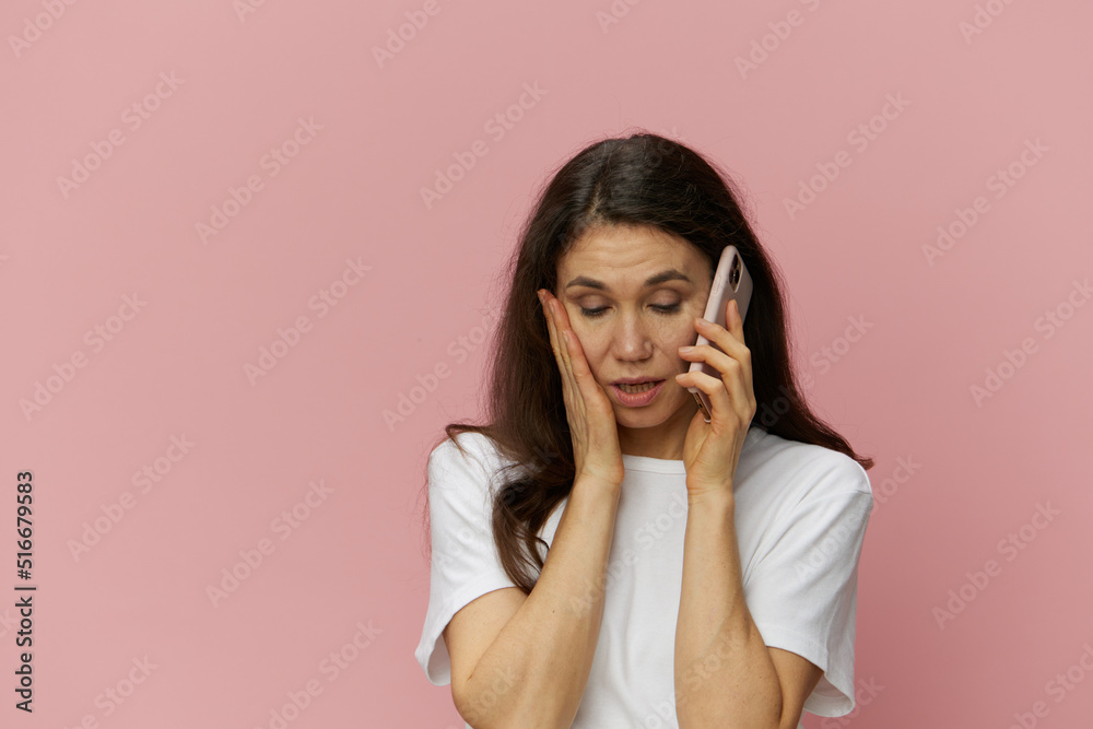 a very puzzled woman stands with her eyes closed in shock with her hand on her forehead and talks on the phone a very puzzled woman stands with her eyes closed in shock with her hand on her forehead and talks on the phone