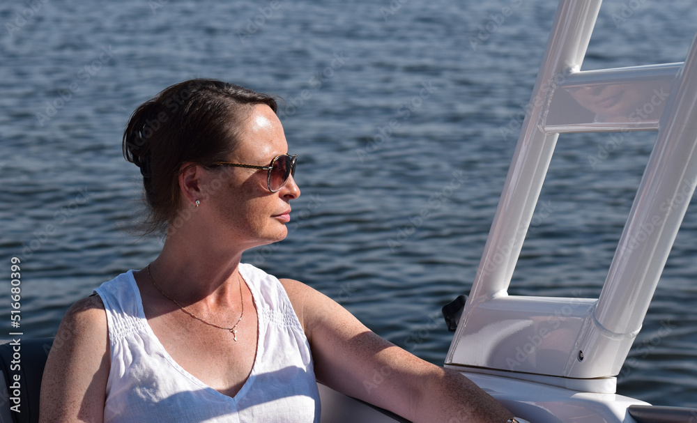 Middle aged woman enjoying sunny day on boat on a lake
