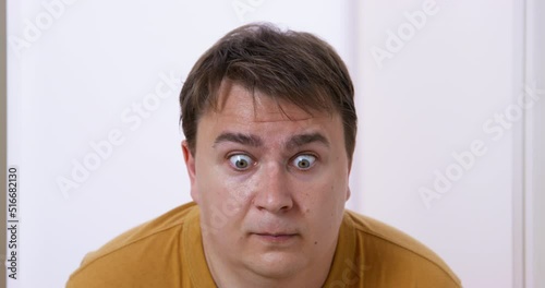 Young man accidentally misbehaved, so he opened his eyes wide in surprise and decided to quietly escape from scene of crime, so that he would not be suspected of making a mess