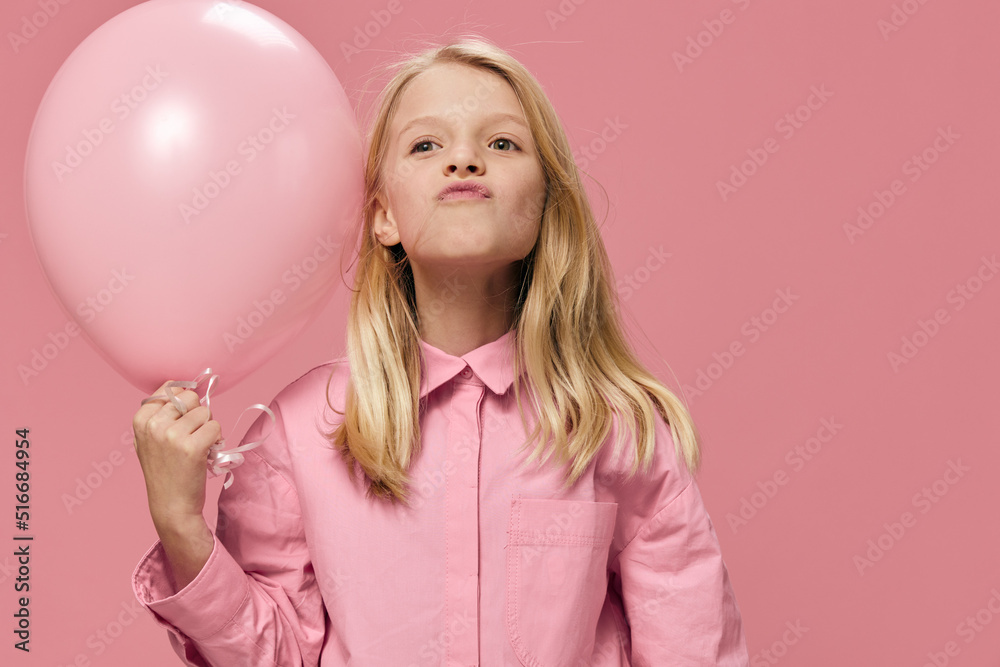 little girl, blonde, stands smiling happily with a pink balloon in her hands little girl, blonde, stands smiling happily with a pink balloon in her hands