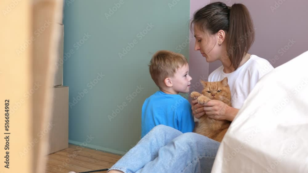 Young mother, a funny child and a ginger cat have fun during the