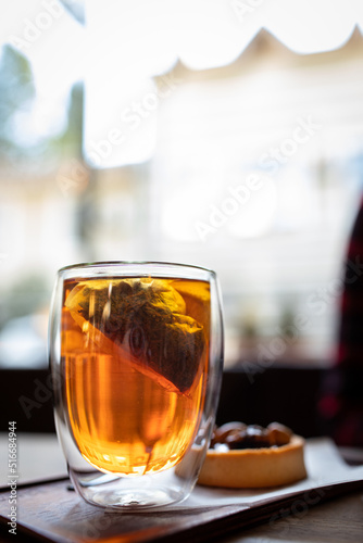 A clear mug of tea with lemon and dessert on the coffee shop table. Macro photo. Vertical photo.