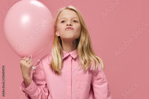 little girl, blonde, stands smiling happily with a pink balloon in her hands © Tatiana