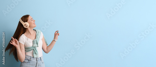 Cool young woman listening to music on light blue background with space for text