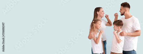 Portrait of happy family brushing teeth on light background with space for text