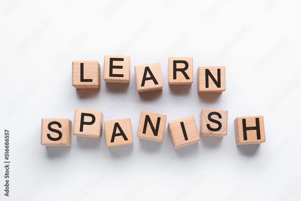 Text LEARN SPANISH made of wooden cubes on white background, top view Text LEARN SPANISH made of wooden cubes on white background, top view