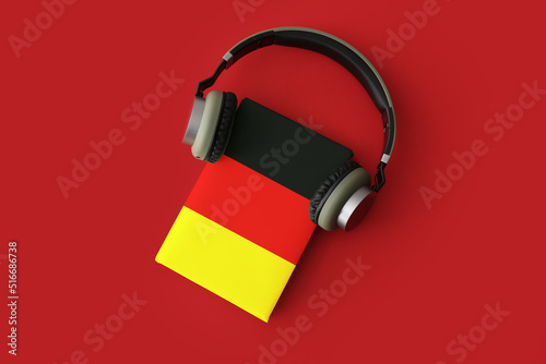 Book and modern headphones on red background. Concept of studying German language