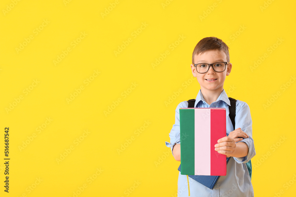 Little schoolboy with book on yellow background. Concept of studying Italian language Little schoolboy with book on yellow background. Concept of studying Italian language