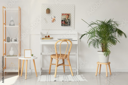 Interior of light office with workplace  pegboard and shelving unit