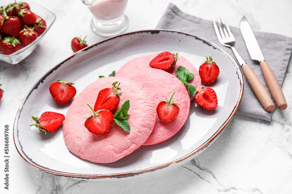 Plate with pink pancakes and strawberry on light background Plate with pink pancakes and strawberry on light background