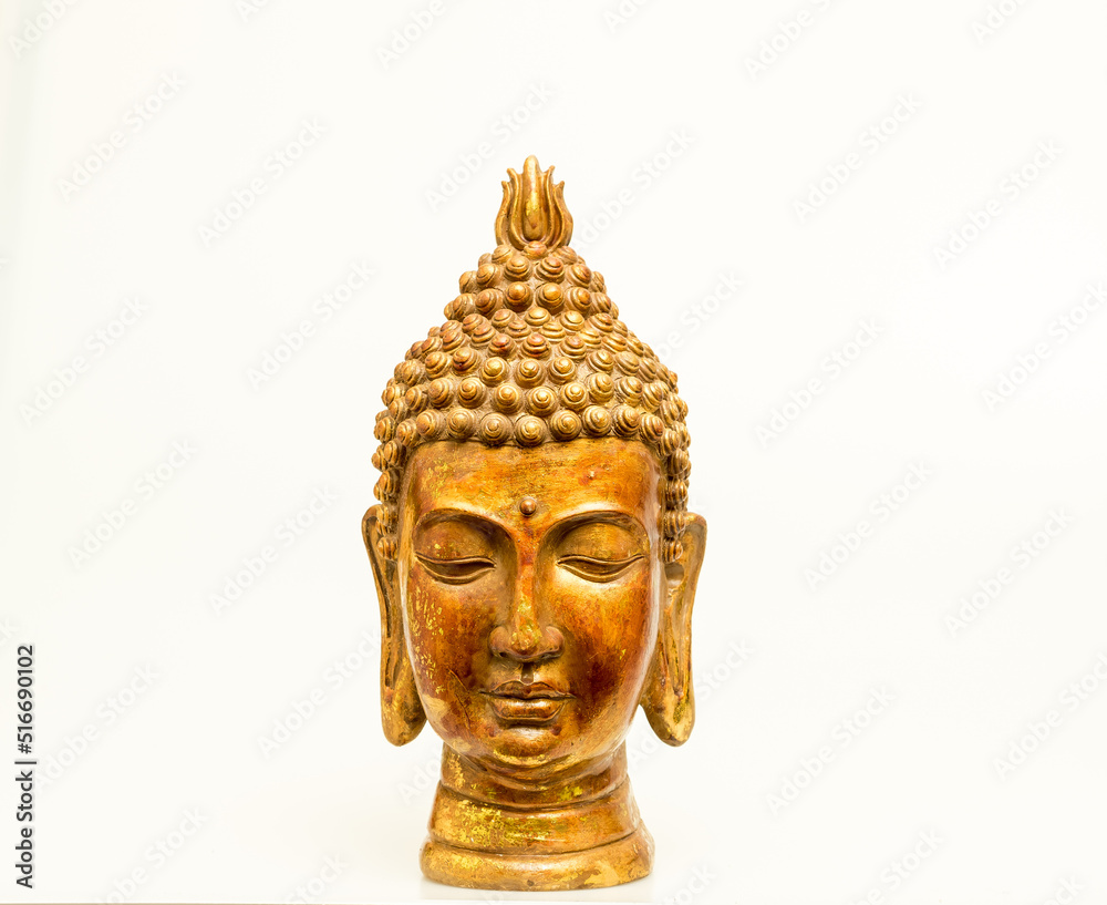 A beautiful hand-carved wooden Buddha head painted in gold isolated against a white background. 