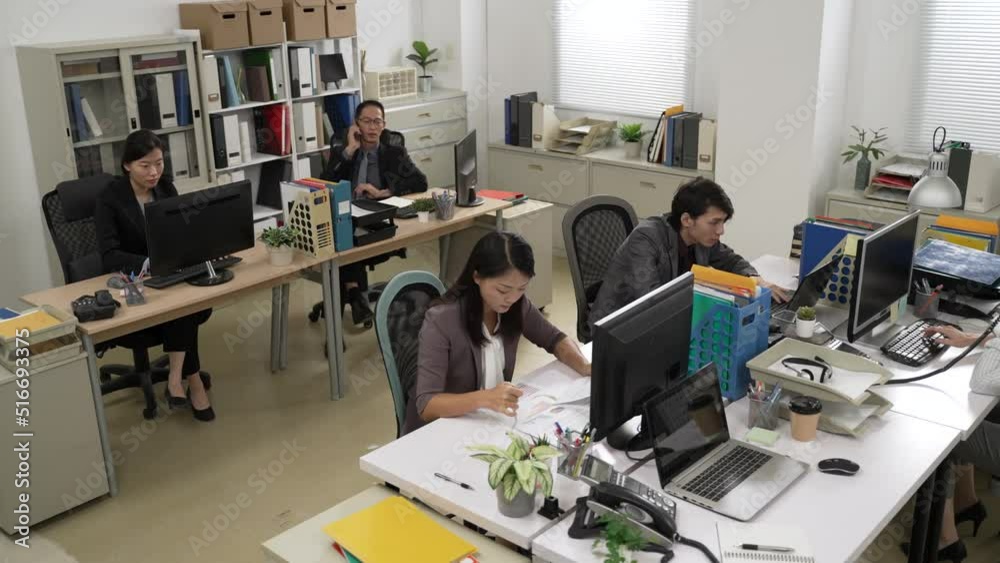 high angle view of a group of busy asian businesspeople wearing suit are working at their desk as a team in a modern office. teamwork concept