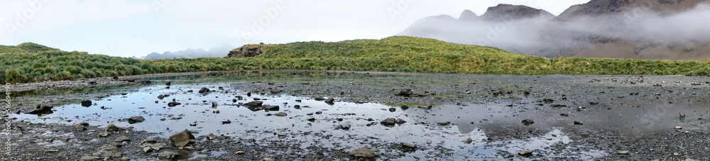 Panorama of a shallow, rocky inland lagoon below cloud shrouded mountains at Jason Harbor, South Georgia Island Panorama of a shallow, rocky inland lagoon below cloud shrouded mountains at Jason Harbor, South Georgia Island