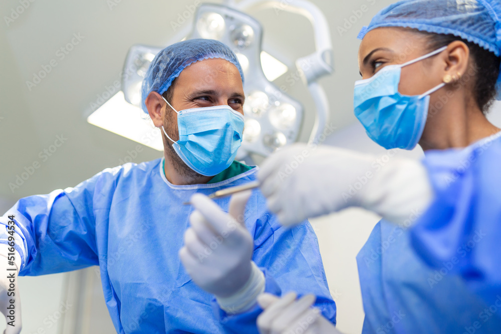 Low Angle Shot in the Operating Room, Assistant Hands out Instruments to Surgeons During Operation. Surgeons Perform Operation. Professional Medical Doctors Performing Surgery. Low Angle Shot in the Operating Room, Assistant Hands out Instruments to Surgeons During Operation. Surgeons Perform Operation. Professional Medical Doctors Performing Surgery.