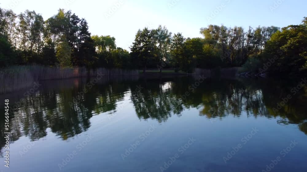 Across empty park bench, glassy lake to the other shore.Perfect aerial view flight overfly drone footage in Brieselang Germany Europe at summer 2022. Across empty park bench, glassy lake to the other shore.Perfect aerial view flight overfly drone footage in Brieselang Germany Europe at summer 2022.