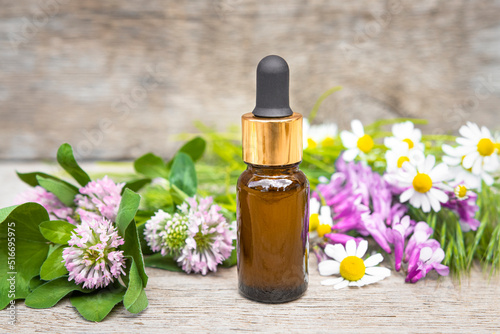 Glass brown bottle with essential oil and wildflowers on a wooden background. Aromatherapy and herbal medicine.
