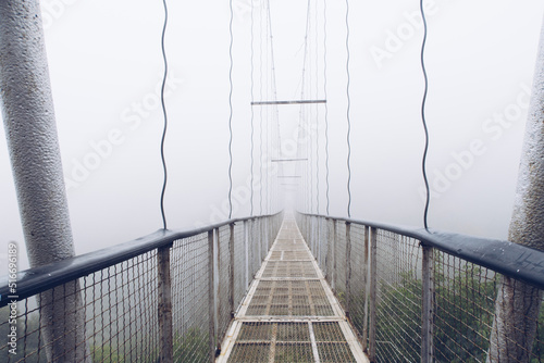 Fog view on the Khndzoresk suspension bridge in the cave city in the mountain rocks. Armenia landscape attraction. Abandoned ruins in the mist. Atmospheric stock photo. photo