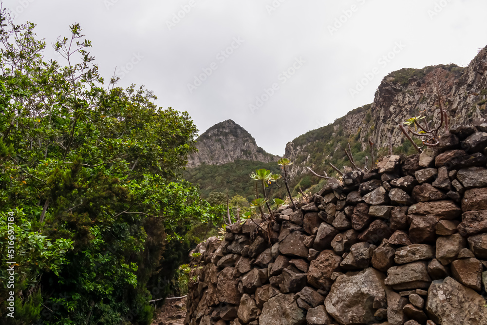 Scenic hiking trail along a massive stone wall leading to village Taganana with view on the Anaga mountain range, north coast of Tenerife, Canary Islands, Spain, Europe. Path from Afur to Taganana