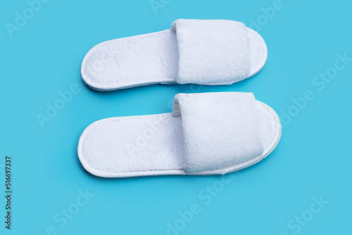 Hotel slippers on blue background. Copy space