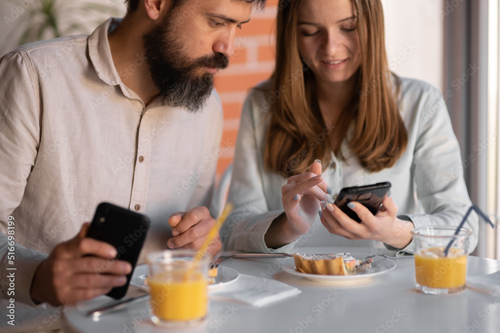 close-up of happy couple using mobile phone together while eating breakfast at home close-up of happy couple using mobile phone together while eating breakfast at home
