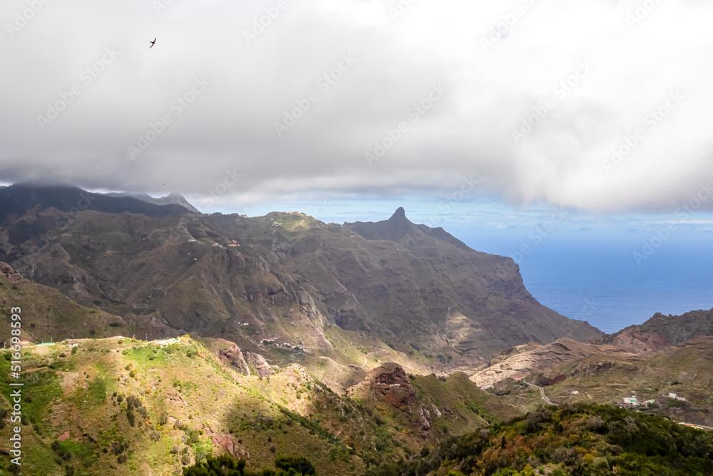 Panoramic view on mountain peak Roque de Taborno in Anaga massif seen from Afur on Tenerife, Canary Islands, Spain, Europe, EU. Curvy road leading to remote mountain villages. Dark clouds emerging