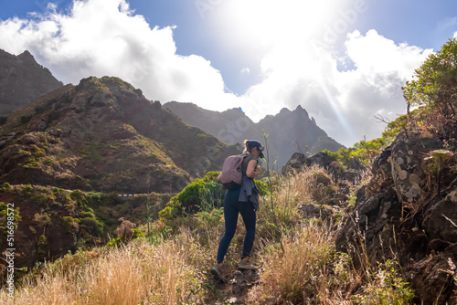 Woman with backpack walking on a panoramic hiking trail in the mountains of Anaga massif between Afur and Taganana on Tenerife, Canary Islands, Spain, Europe. Hill landscape in UNESCO Anaga rural park photo