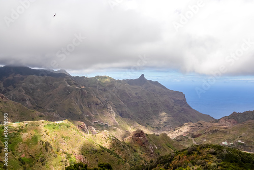 Panoramic view on mountain peak Roque de Taborno in Anaga massif seen from Afur on Tenerife, Canary Islands, Spain, Europe, EU. Curvy road leading to remote mountain villages. Dark clouds emerging