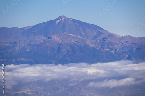 Window view from an airplane on the volcano mountain peak of Pico del Teide on Tenerife  Canary Islands  Spain  Europe  EU. High peak are shrouded in clouds. Flying high above the ground. Freedom