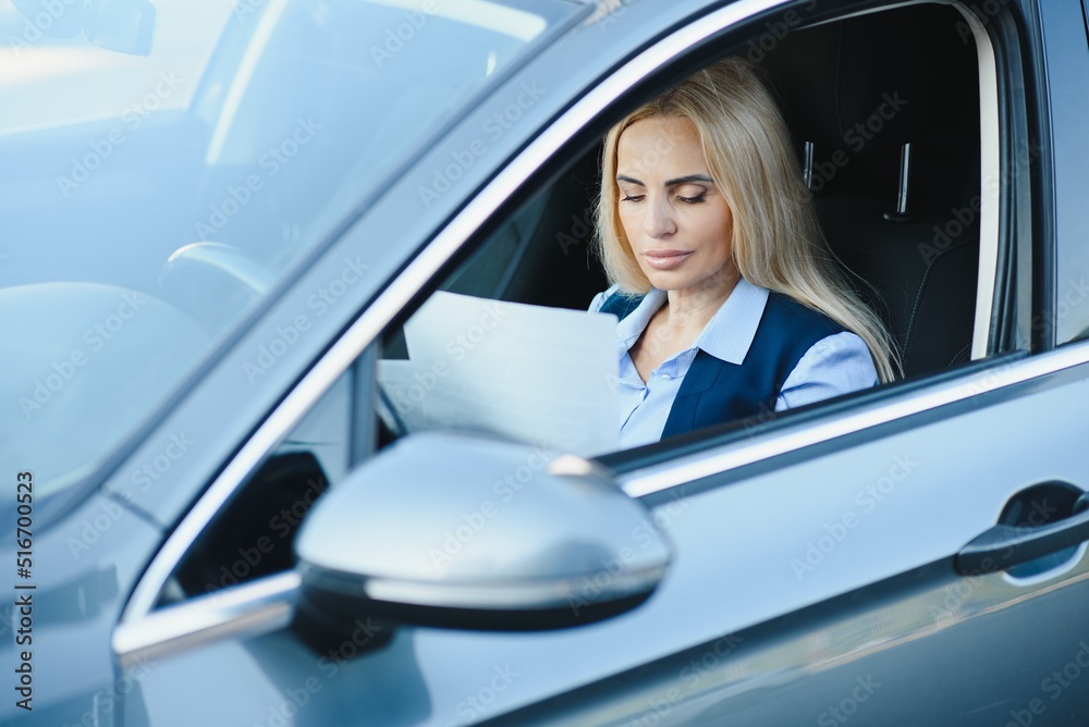 Fashion business woman with financial papers by her car