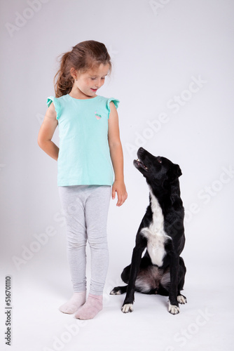 Cute little girl with her best pet friend black female dog on white backround.