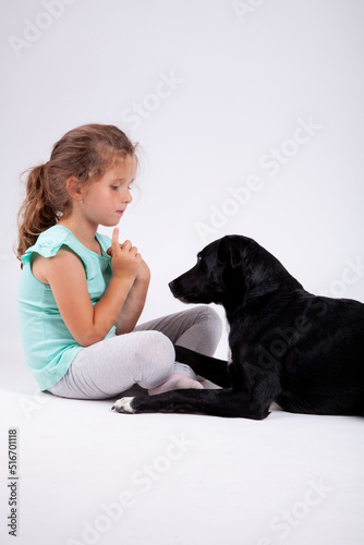 Cute little girl with her best pet friend black female dog on white backround.